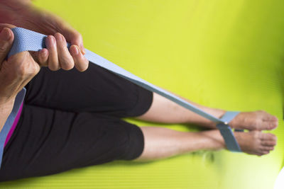 Low section of woman exercising with belt at home