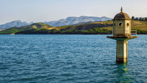 View of a lake with mountain range and a tower in the background