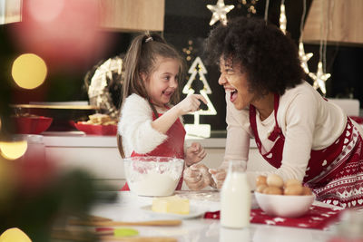 Smiling woman with daughter preparing food during christmas in kitchen at home
