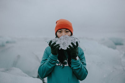 Portrait of girl wearing knit hat holding ice during winter