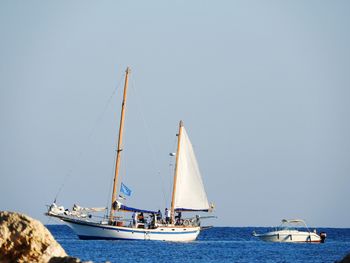 Sailboats sailing on sea against clear sky