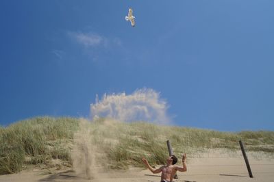 Low angle view of people against blue sky