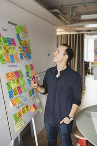 Smiling businessman looking at whiteboard in board roam