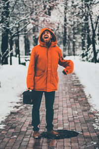 Full length portrait of woman standing on footpath during winter