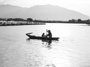 Mother with son sailing on boat in river against mountains