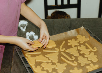 One girl bakes cookies, placing the dough on a baking sheet.
