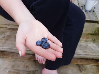 Low section of woman holding blueberries in her hand 