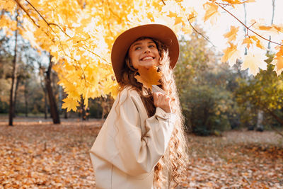 Portrait of young woman wearing hat standing on field