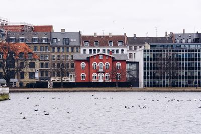 Buildings by river against sky in city