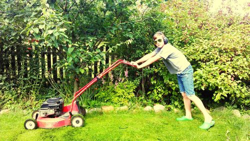 Portrait of boy using lawn mower in yard