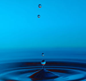 Close-up of drop falling on blue surface