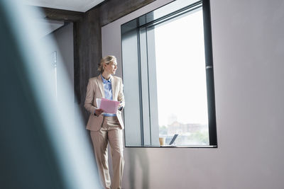 Businesswoman standing at the window holding document