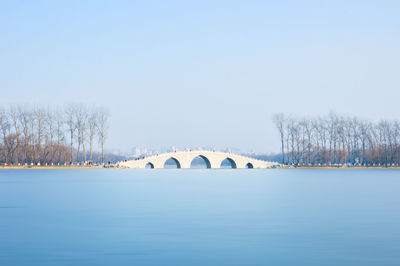 Bridge over river against clear sky during winter