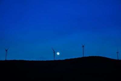 Low angle view of silhouette wind turbines against sky during sunset