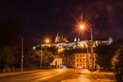 Illuminated city street against sky at night