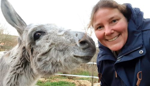 Portrait of smiling young woman with donkey outdoors