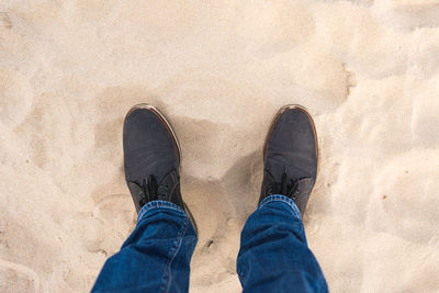 Low section of man standing on sand