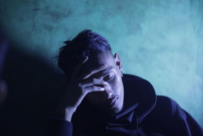 Depressed man sitting against wall