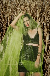 Portrait of woman covered in netting while standing against plants