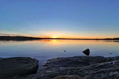 Scenic view of lake against clear sky at sunset