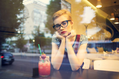 Portrait of young woman looking at illuminated restaurant