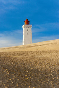 Lighthouse on beach against sky