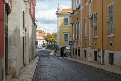 People walking on footpath amidst buildings in city