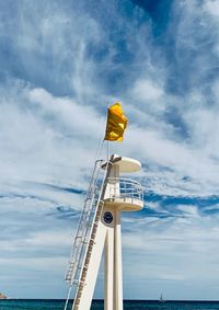 Low angle view of yellow flag on sea against sky