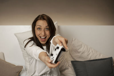 Portrait of smiling young woman holding sofa at home