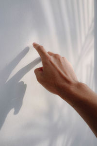 Close-up of hand touching white wall