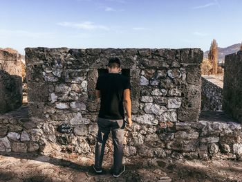 Full length of man standing against stone wall