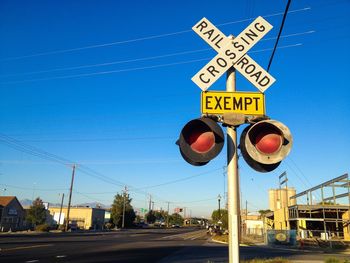 Low angle view of railroad crossing sign against blue sky