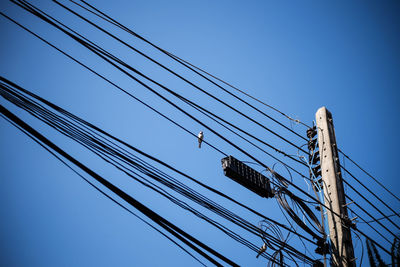 Low angle view of power lines against clear blue sky