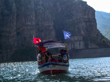 People in boat on sea against mountain