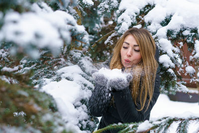 Portrait beautiful girl in winter snowy day near fir tree in forest. young