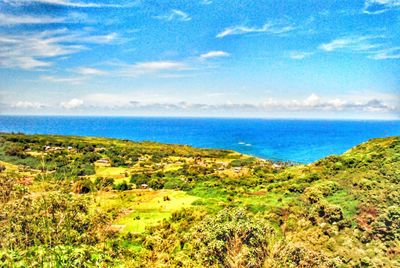 Scenic view of sea and green field against sky