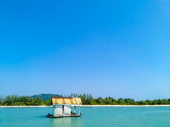 Boat in sea against clear blue sky