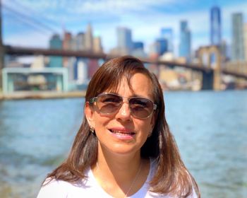 Portrait of woman with brooklyn bridge over east river in background