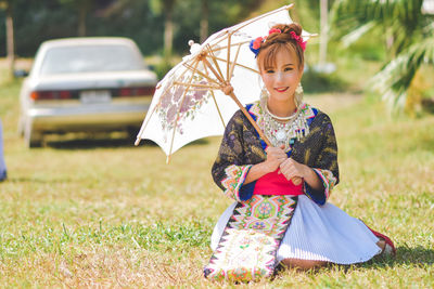 Woman holding umbrella on field