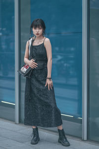 Portrait of young woman standing against window