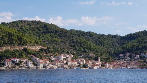 Scenic view of townscape by sea against sky
