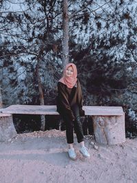 Full length of smiling woman sitting outdoors