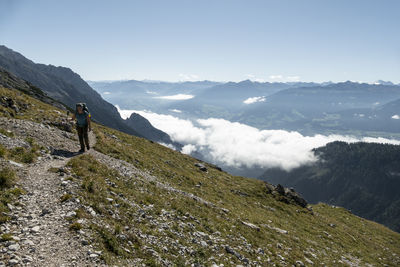 Rear view of man walking on mountain against sky