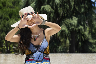 Midsection of woman wearing hat standing against tree