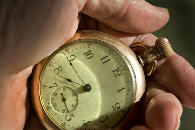 Cropped hand holding pocket watch