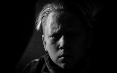 Close-up portrait of serious boy in darkroom