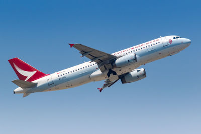 Low angle view of airplane flying against clear blue sky