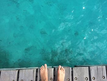 Low section of person standing on pier by sea