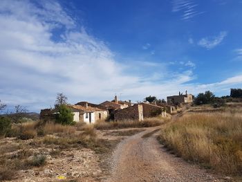 Houses on field by road against sky