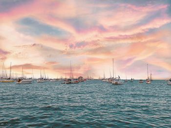 Sailboats in sea against sky during sunset